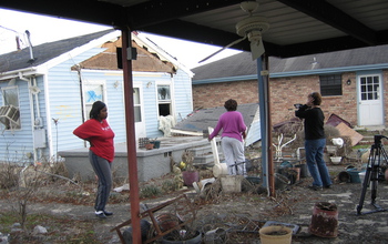 Three women next to houses damaged by storm